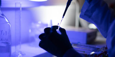 Scientist pipetting sample in blue-lit laboratory.